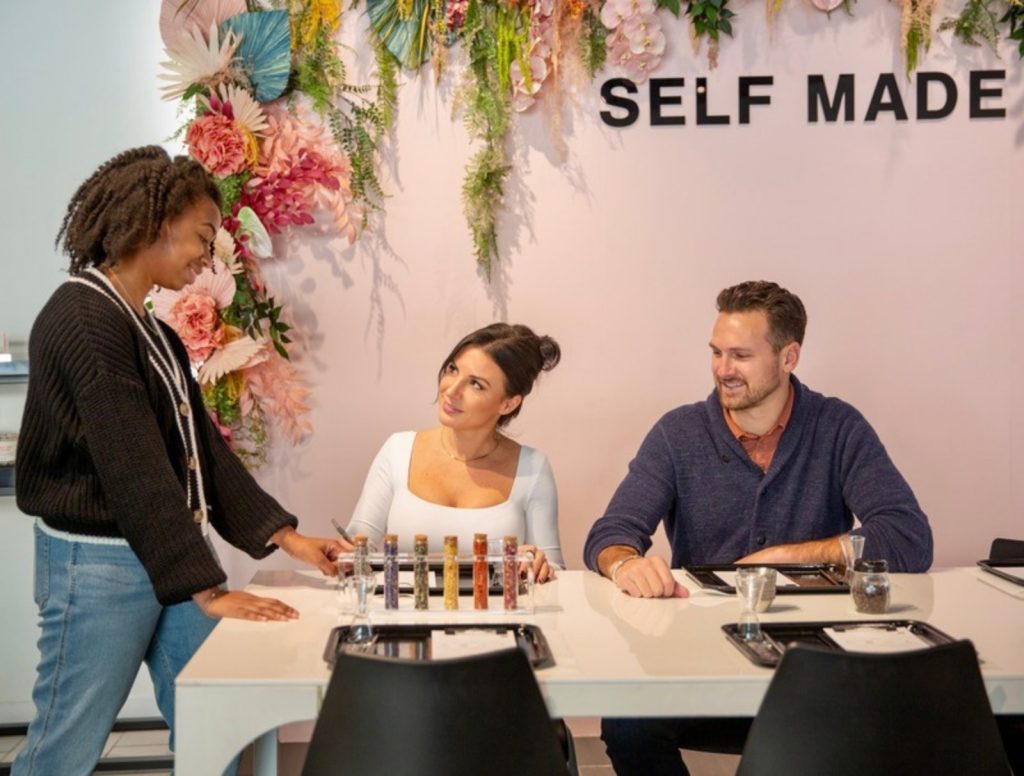 Blank Mason host guiding two guests through making their candles at the SELF MADE wall